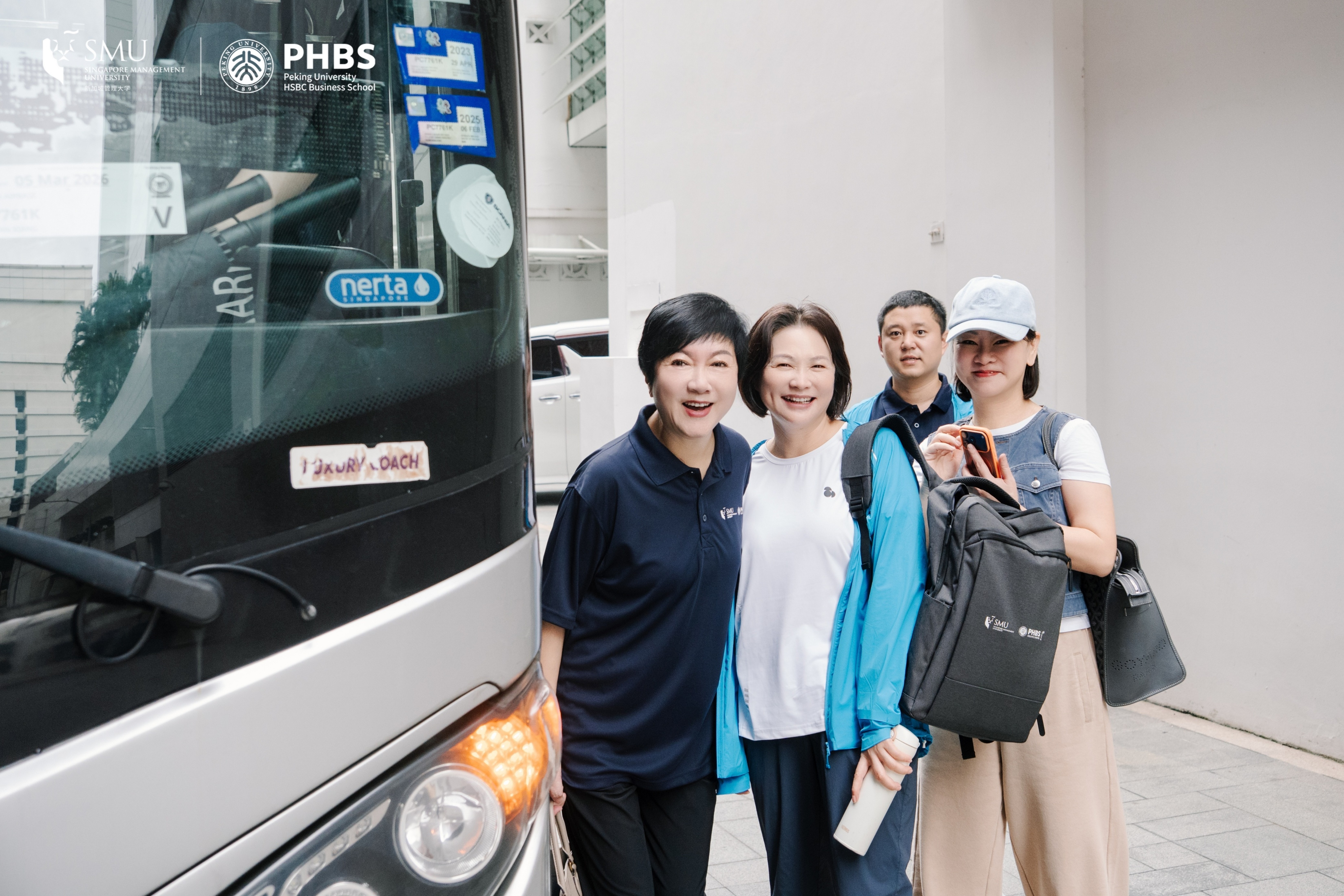 students taking a photo beside a bus